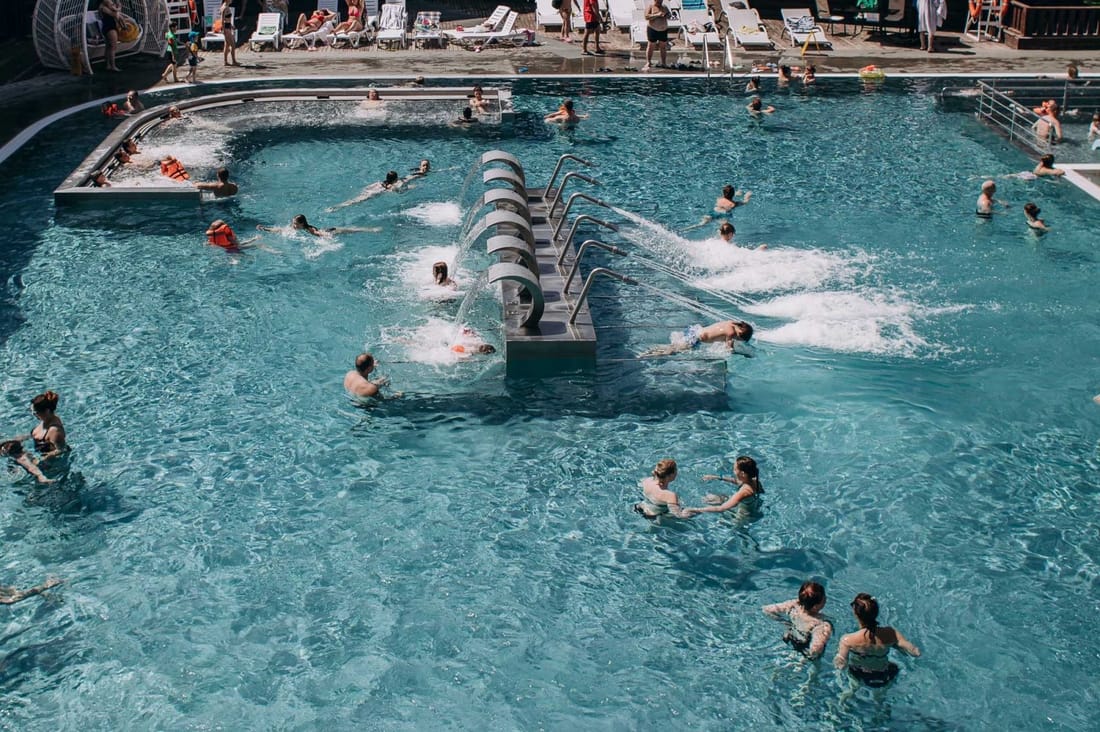 A thermal pool lined in PVC membrane, seen from above with people swimming in it