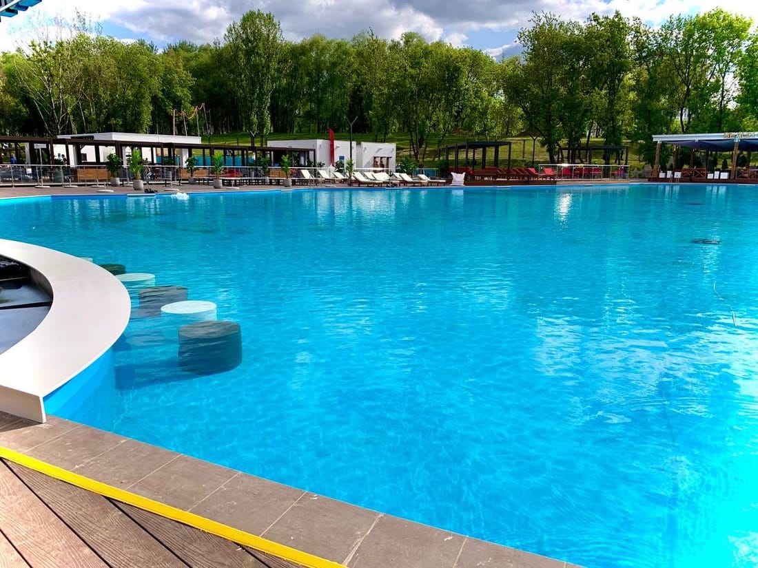 A very large outdoor pool lined in PVC membrane, full of clear turquoise water