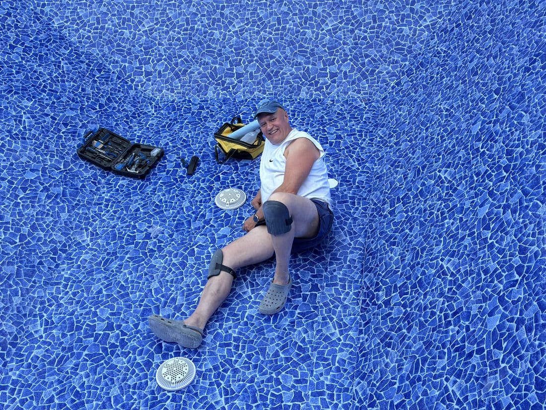 A worker sitting on a finished blue mosaic membrane floor