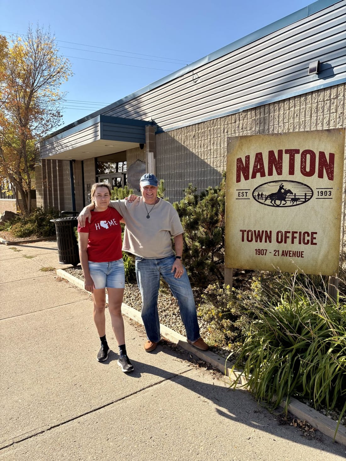 Two people in front of the Nanton Town Office sign, Alberta