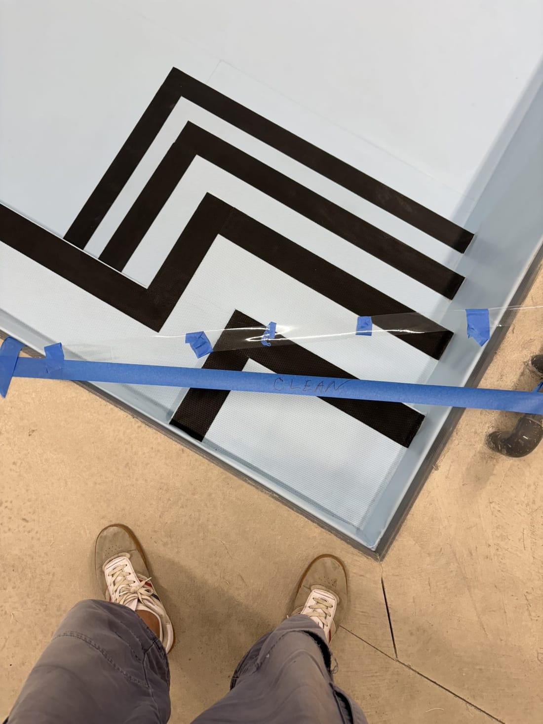 A white deck with a black chevron pattern being welded, the tools beside it