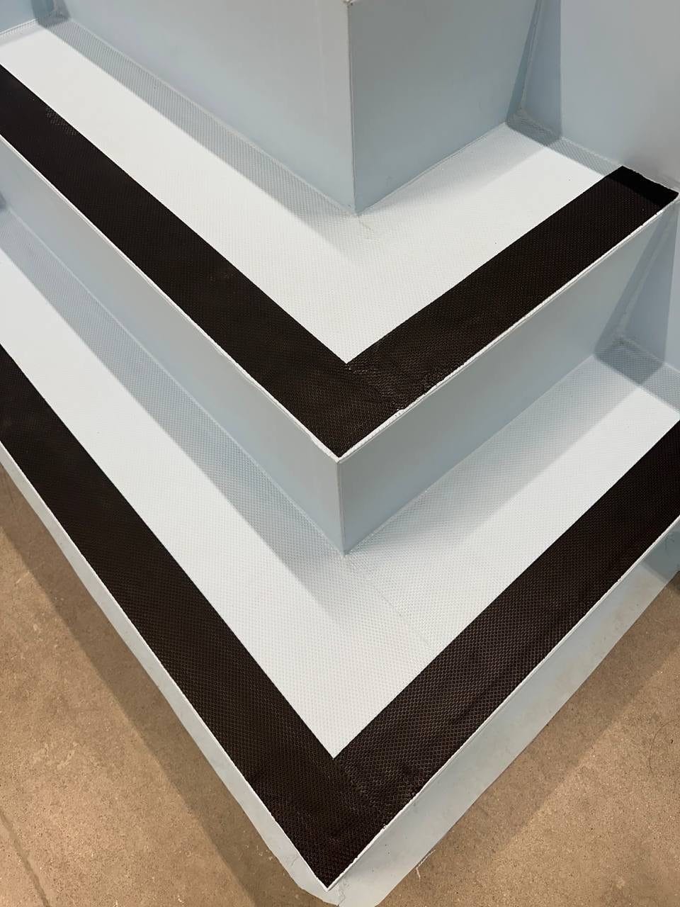 A deck corner in white membrane with a black chevron pattern welded into it