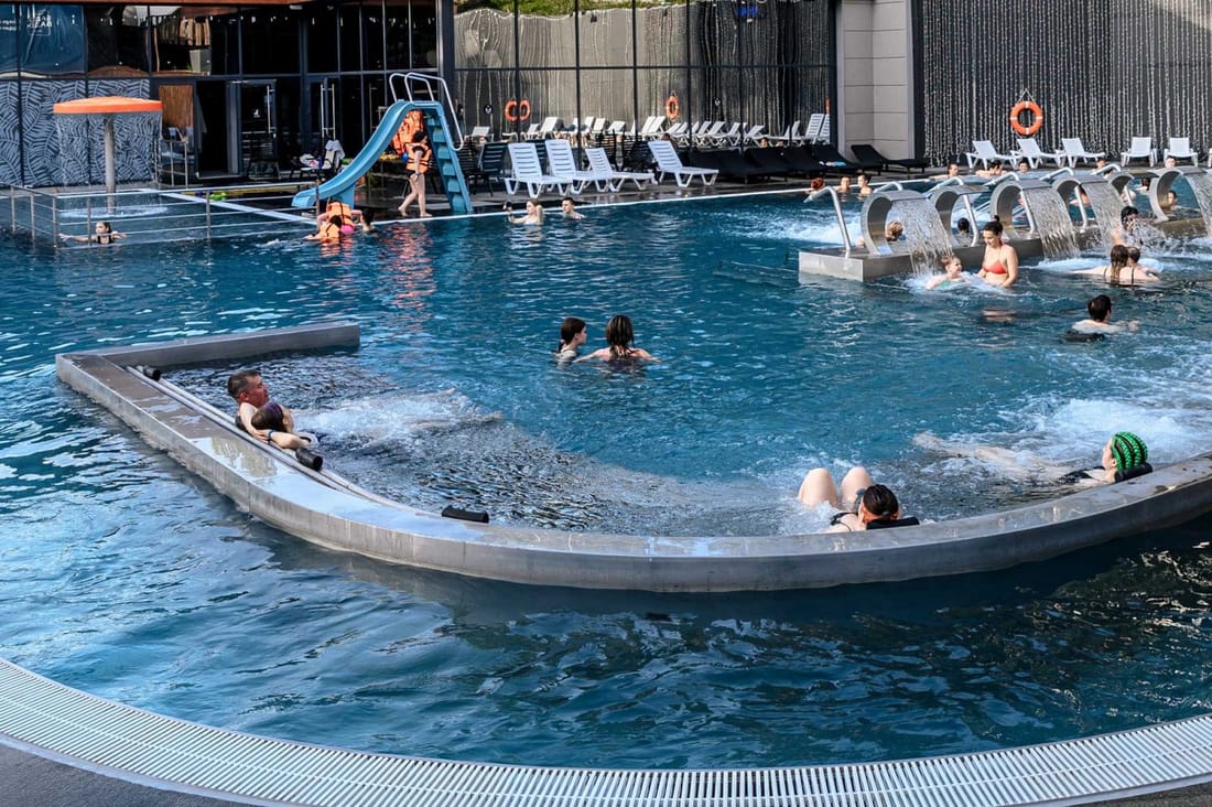 A thermal pool lined in PVC membrane, seen from above with people swimming in it
