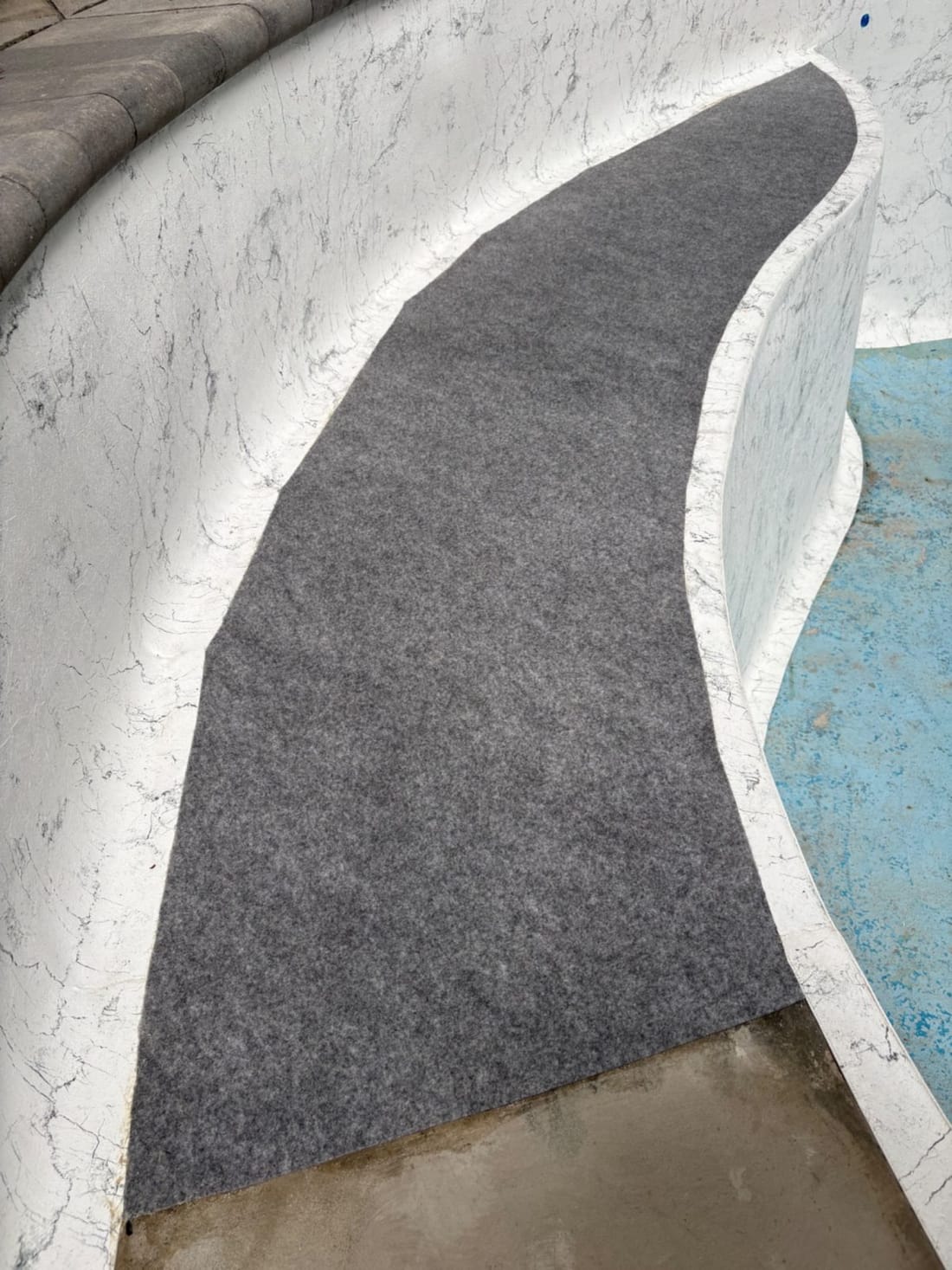 Grey geotextile underlay laid over the curved steps and floor of a pool