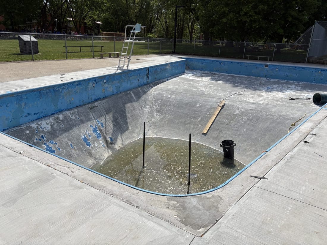 An empty, worn pool shell before renovation