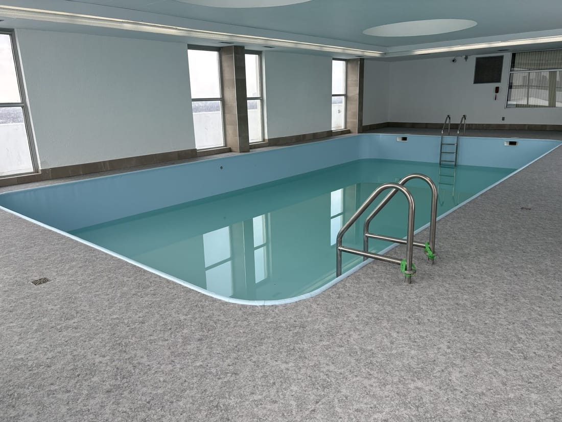 A finished indoor pool lined in light blue membrane