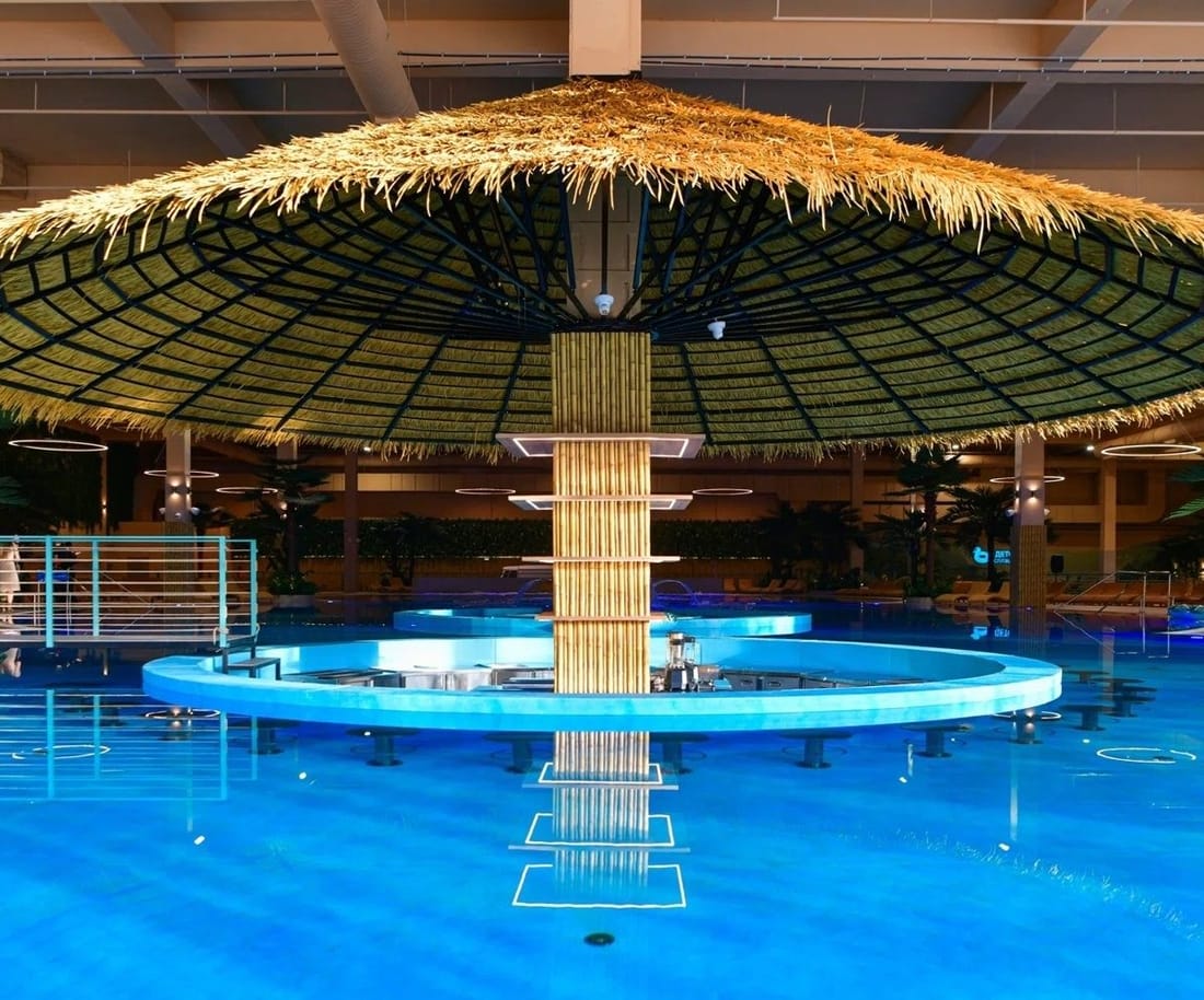 A water park pool with a thatched bar standing in the water