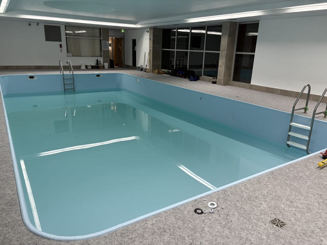 An indoor pool lined in light blue membrane