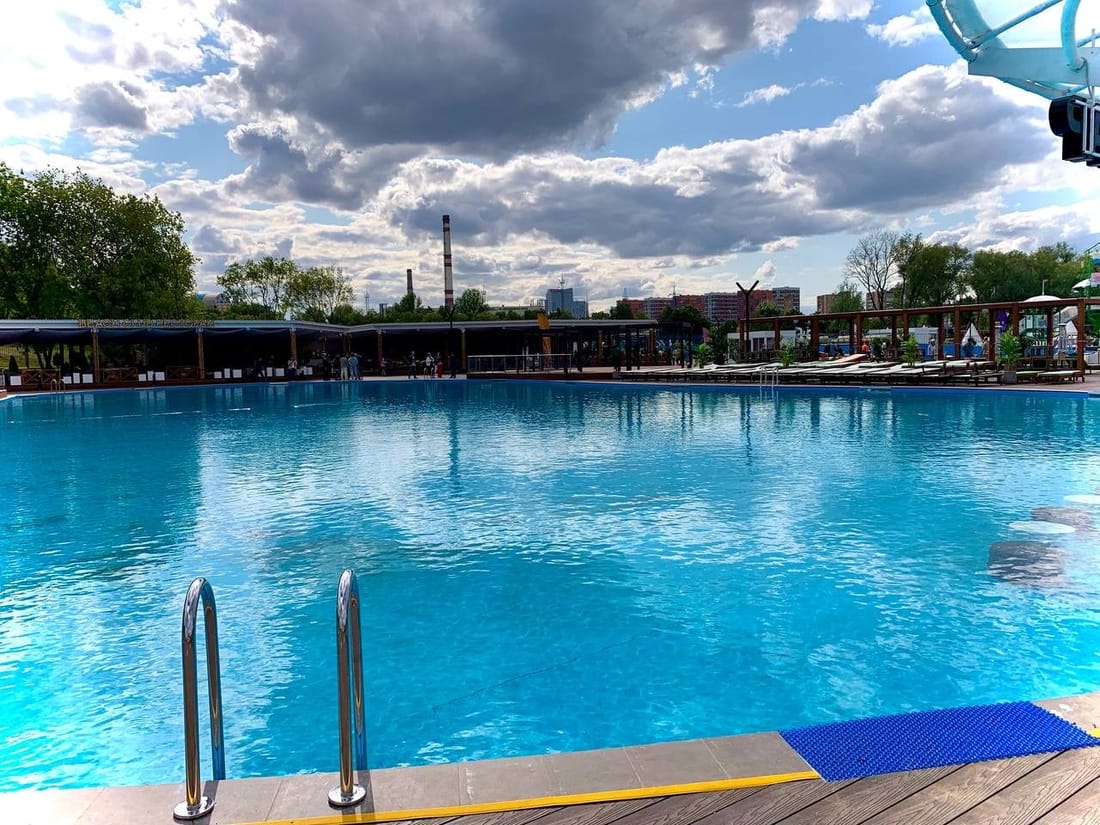 A very large outdoor public pool under a cloudy sky