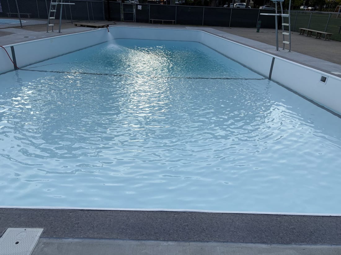 Sunlight on the water of a pool lined in white membrane